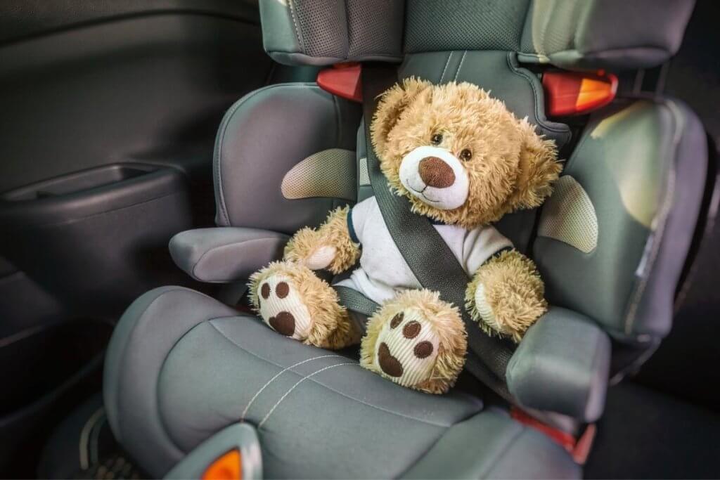 teddy strapped into an infant car seat - toys for car trips