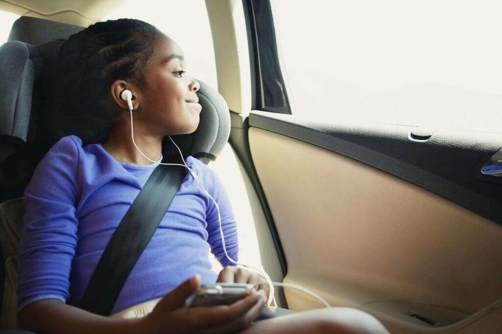 Child listening happily to headphones in a car