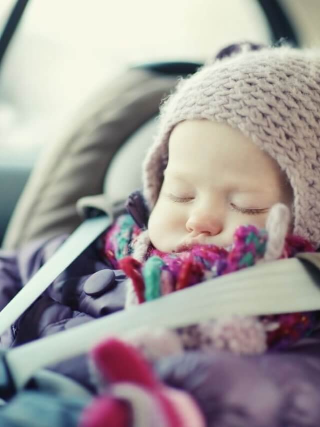 A baby in a car seat wrapped in warm jacket and beanie