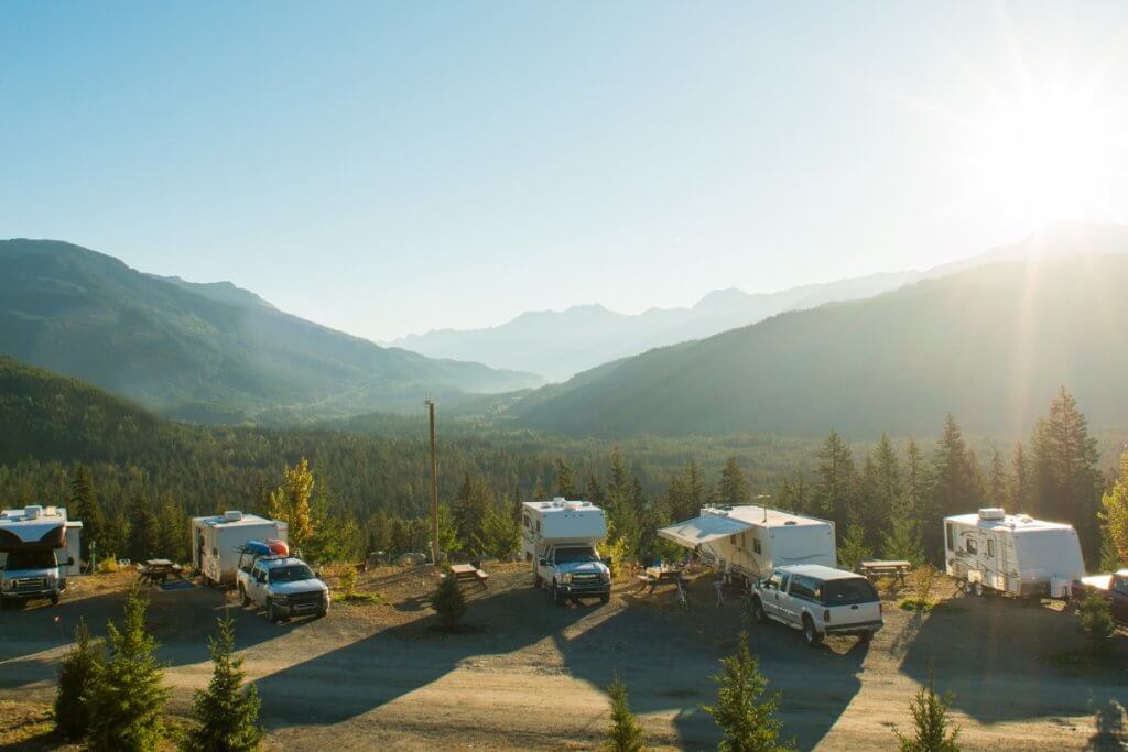 a selection of RV vehicles parked in a line camping in a glorious sunny location - rv rentals comapred